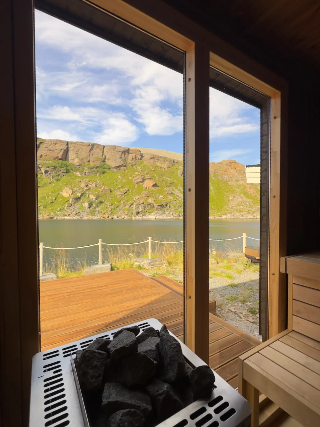 The sauna at Myrfjord, with its heater, wooden bench and windows overlooking the fjord.