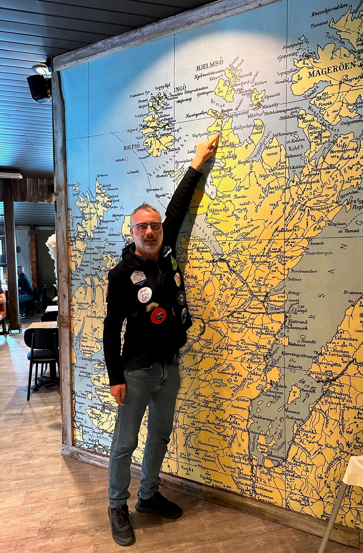 A man points to Northern Norway on a large map.