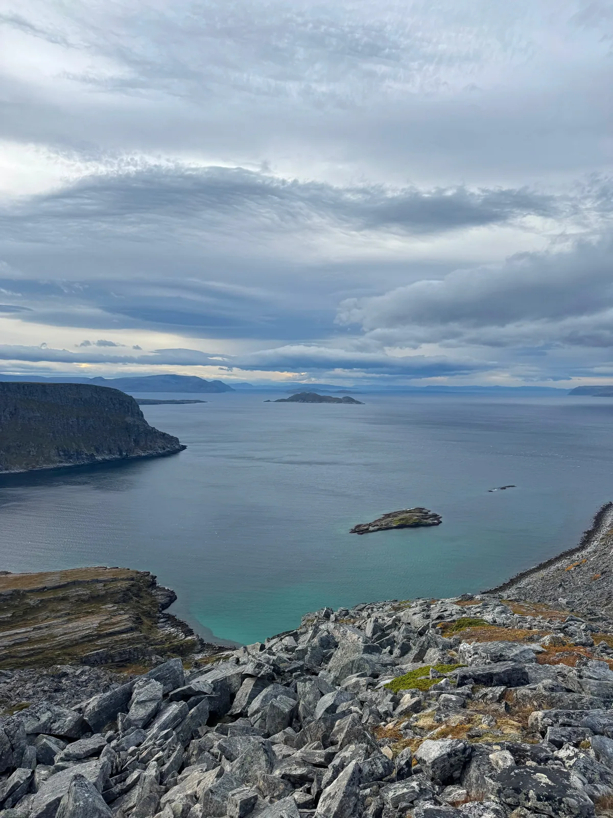 A bay with rocky islets seen from a cliff above the coast.