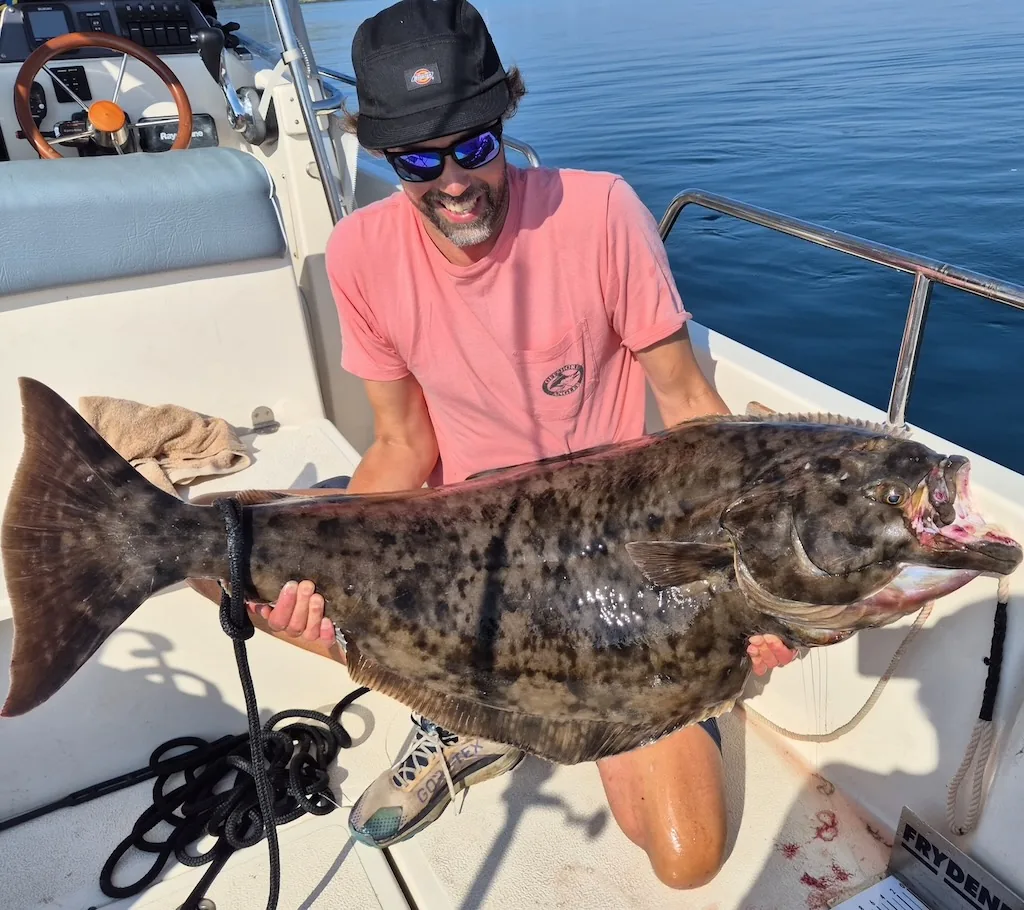 Angler holding a large flatfish aboard a boat